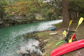 a beautiful view of a riverbank and the river that flows through the HEB preserve/camp area.  a kayak and conoe on the bank